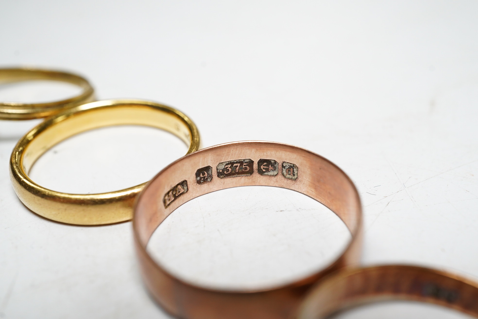 Five assorted rings: a 22ct gold band, size L, 4.2 grams, a 9ct rose gold band, size O, 2.1 grams, a 9ct gold signet ring, size M, 2.1 grams, a red cabochon set yellow metal ring, size I, gross 1.4 grams and a cameo set